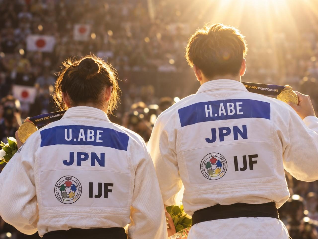 Two judoka seen from behind showing their gold medals