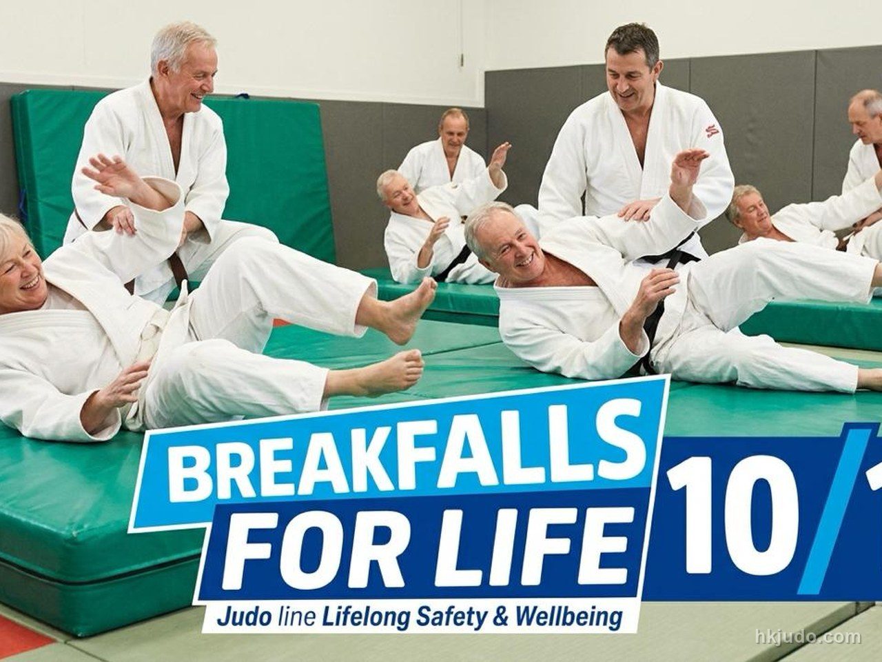 多名成年人在道場的綠色軟墊上練習柔道受身，背景有「BREAKFALLS FOR LIFE」標示
