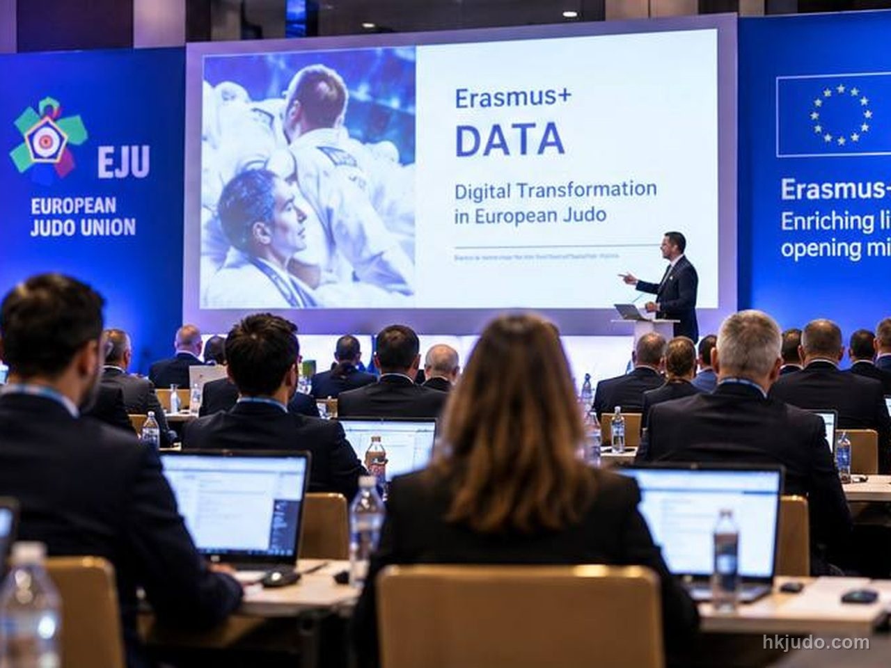 ステージ上の登壇者と、Erasmus+ DATAと記されたスクリーン、両脇に並ぶEJUとErasmus+のバナー