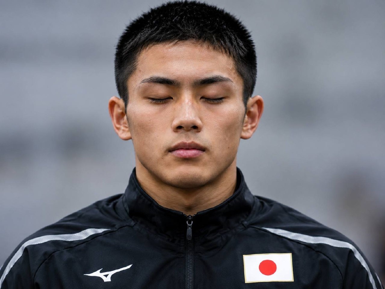 胸に日の丸が入った黒い日本代表ジャケットを着た選手。