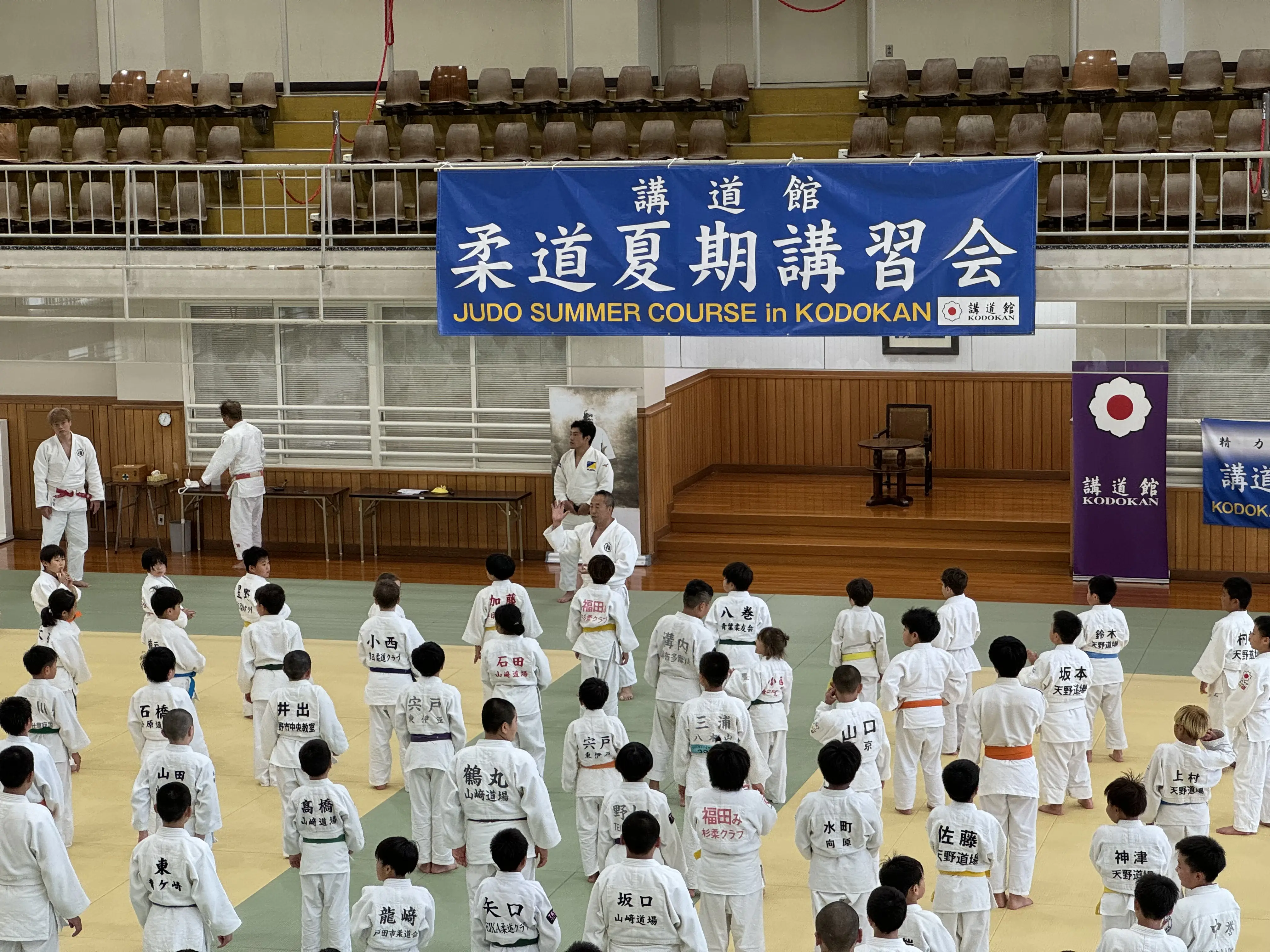 A Kodokan summer course inside the dojo, with young judoka listening to instruction