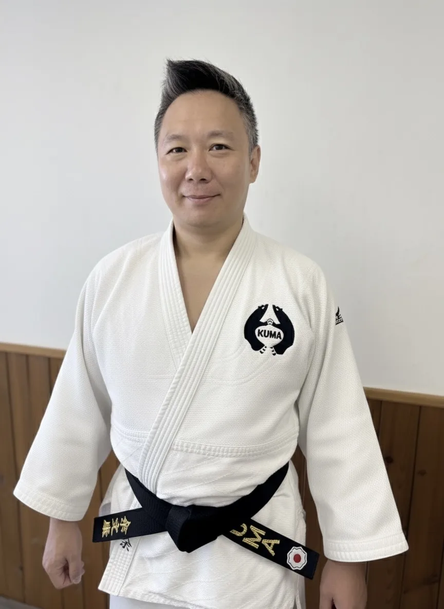 Kuma Dojo adult judoka wearing a white judogi and black belt in the dojo