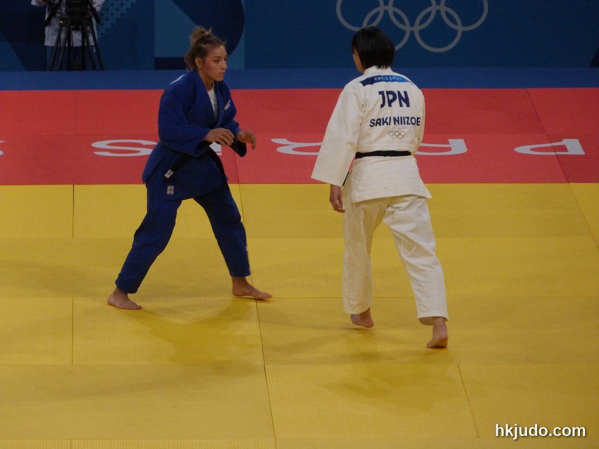Saki Niizoe of Japan, seen from behind in a white judogi with JPN on her back, facing her Serbian opponent at the Paris 2024 Games